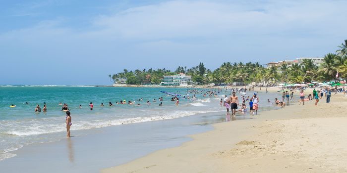 Menschen baden im Meer und liegen am Sandstrand