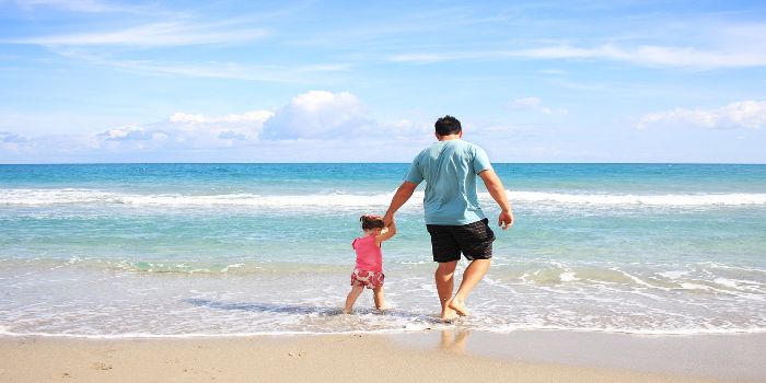 Ein Vater geht mit seinem Kind am Strand spazieren