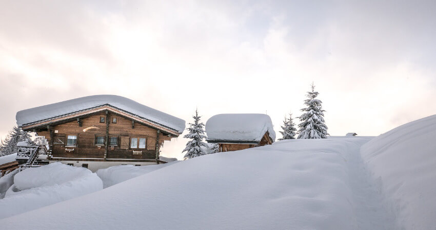 Ein Holzhaus mit viel Schnee auf dem Dach.
