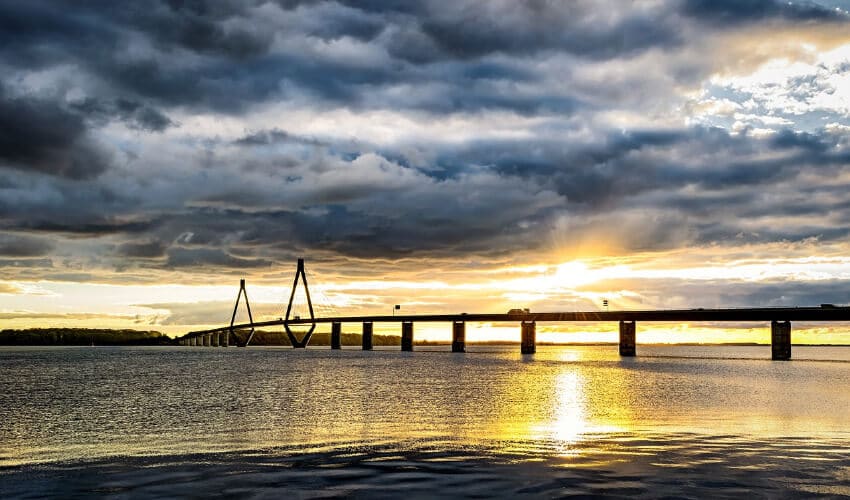 Eine lange Brücke auf Betonstehern in der Abenddämmerung.