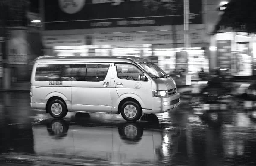 Ein Kleinbus flitzt bei Regen durch die Straßen.