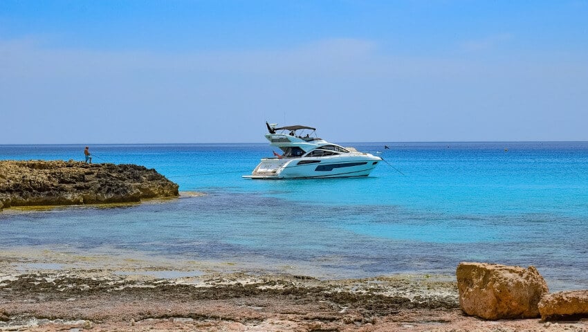 Ein Yacht ankert alleine vor einer felsigen Küste.