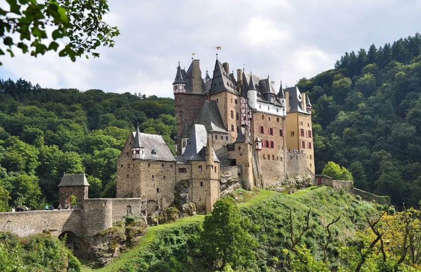 Eine Burg aus Steinen und roten Fenstern auf einem Hügel.