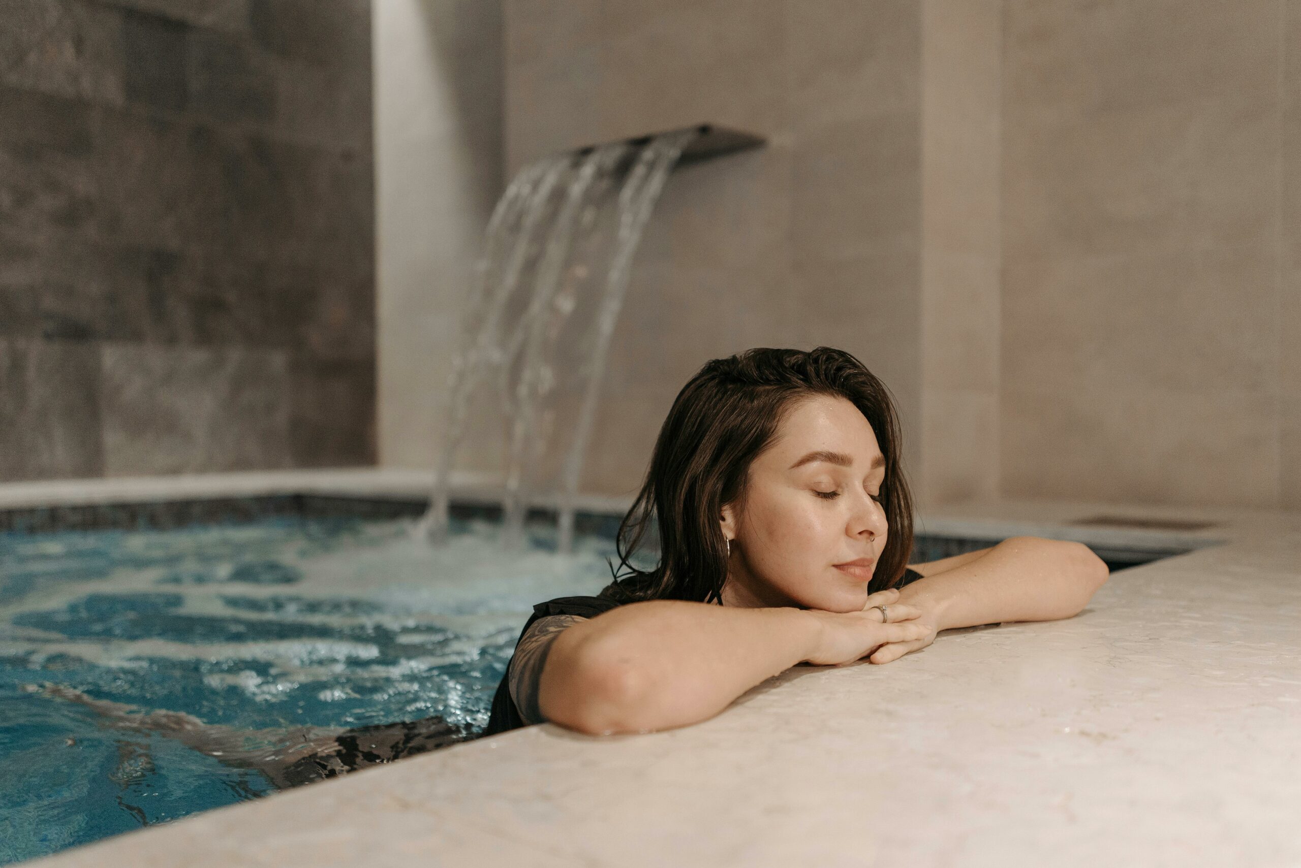 Eine Frau entspannt sich im Wasserbecken eins Spa bereichs.