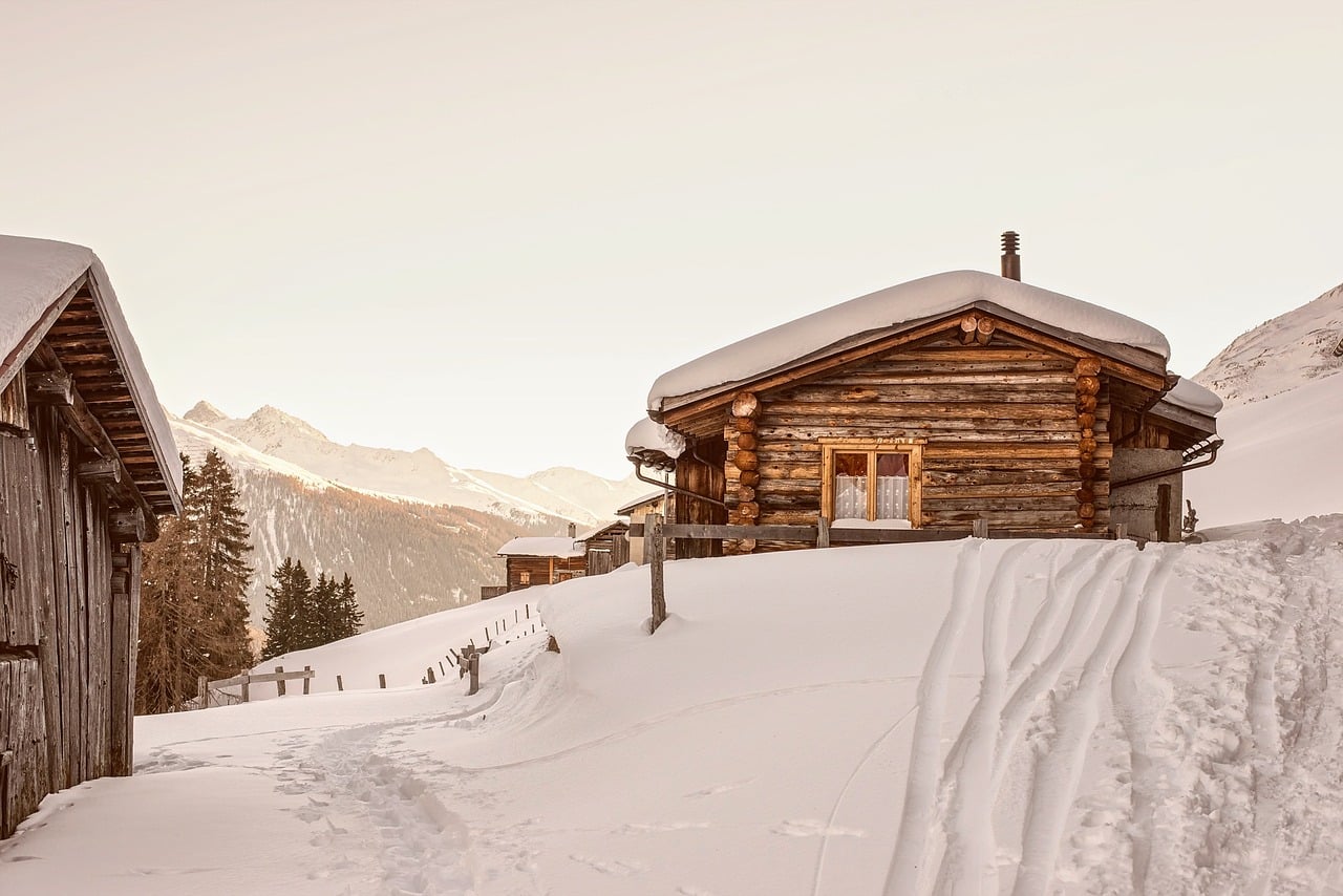 Ein Blockhaus mitten in einer tief verschneiten Winterlandschaft.